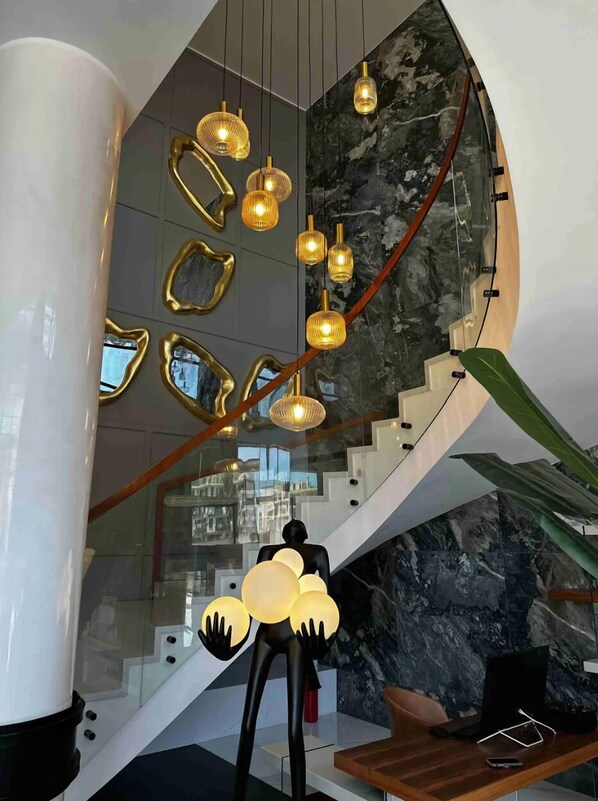 A modern interior with a curved staircase, a glass railing, and a decorative light fixture. - ONYX By Luna Hotel (Oran)
