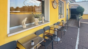 A yellow building with outdoor seating, a window with a reflection, and a sign reading 'ENTRATA'. - Albergo Nuova Aurora  (Mestre)