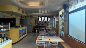 A restaurant with a counter, tables, chairs, and a large window. - Albergo Nuova Aurora  (Mestre)