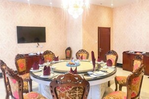 Una sala de conferencias con una mesa redonda, sillas, una televisión y una puerta.