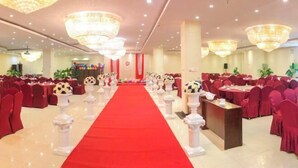 A banquet hall with a red carpet aisle, round tables, and red chairs.