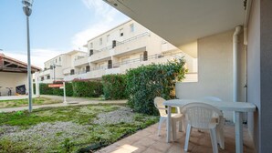 Une terrasse avec une table et des chaises, un lampadaire et un bâtiment en arrière-plan.