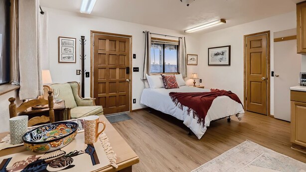 A well-lit bedroom with a bed, bedside tables, a chair, and a window.