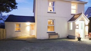 Ein zweistöckiges Haus mit Veranda, einer Bank und Topfpflanzen.