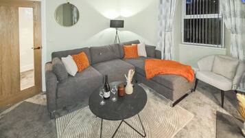 A living room with a grey sofa, a white armchair, a black coffee table, and a patterned rug.