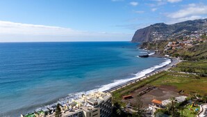 A coastal hotel with a view of the ocean and a mountainous backdrop. - Solar do Mar by LovelyStay (Funchal)