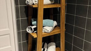 Ein Holzregal mit mehreren Ablagen, auf denen gefaltete Handtücher liegen.