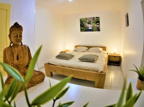 A bedroom with a wooden bed, two bedside tables, a wall-mounted picture, and a Buddha statue. - Le Salséro - Large, cozy *** apartment for 8 people, with parking included, (Nîmes)
