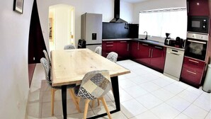 Eine moderne Küche mit Essbereich, ausgestattet mit einem Holztisch, gemusterten Stühlen, einem Einbauofen und einer Mikrowelle.
