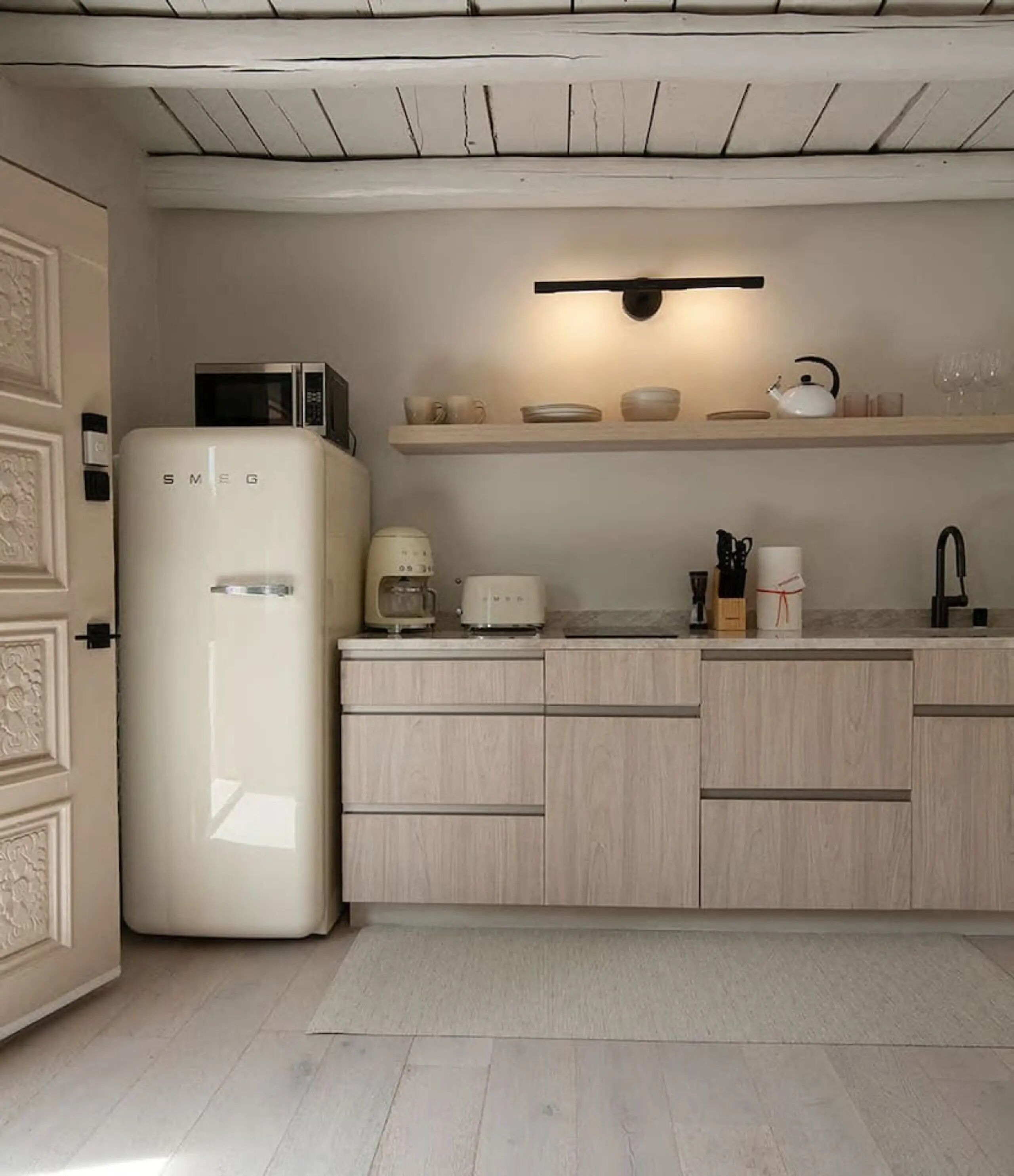 A compact kitchen with a white refrigerator, a microwave, a coffee maker, a toaster, and a sink.
