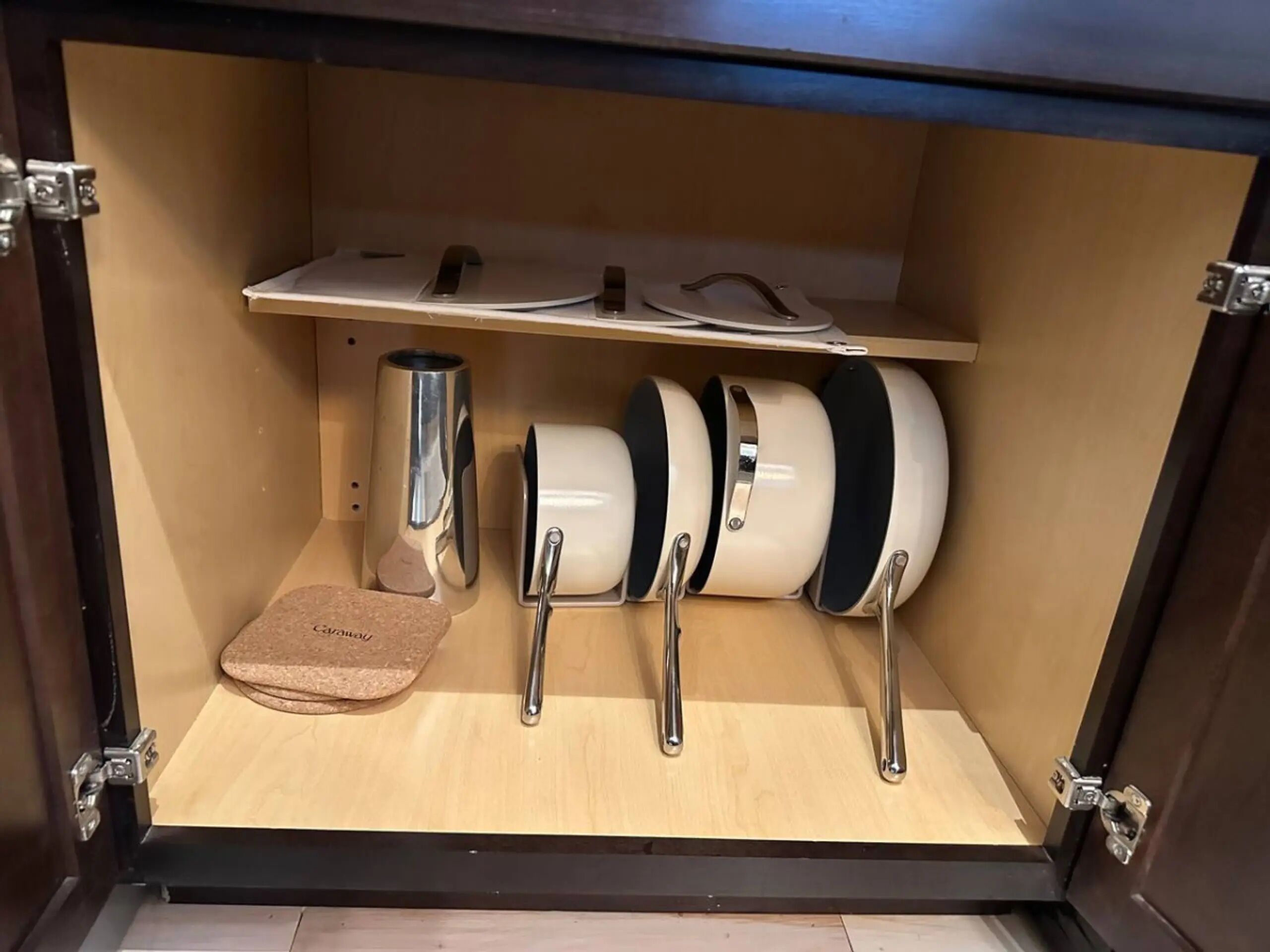 Een keuken met een houten aanrecht, een roestvrijstalen koffiezetapparaat en drie witte en zwarte mokken op een rek.