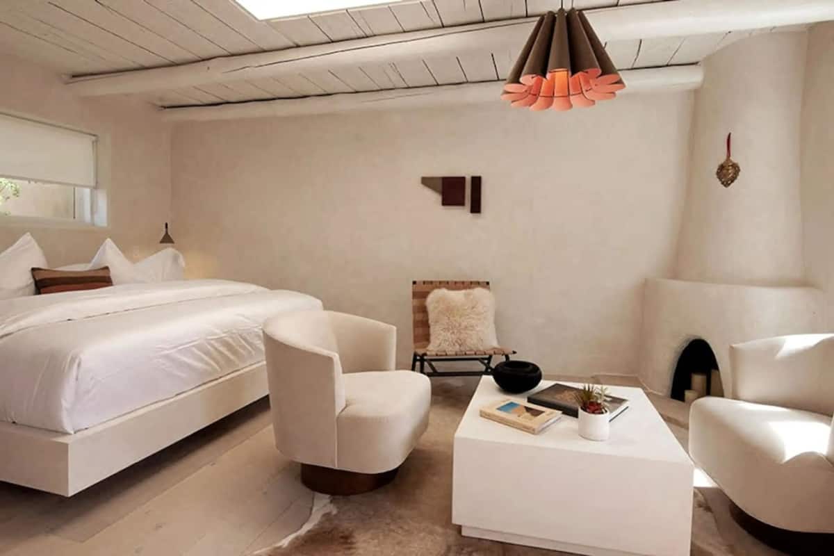 Un dormitorio moderno con una cama grande, dos sillones, una mesita de centro y una chimenea.