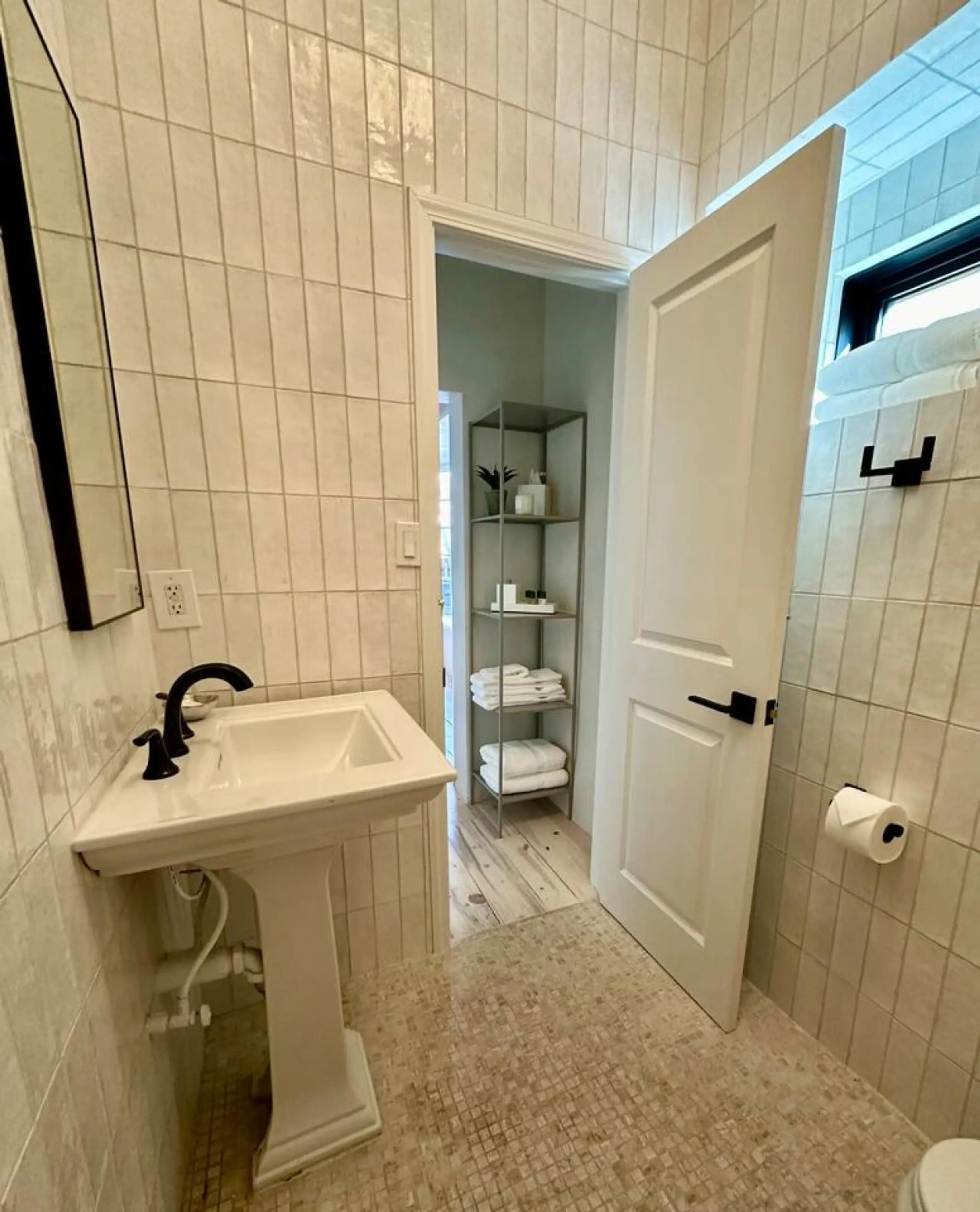 A bathroom with a pedestal sink, a towel rack, and a toilet.