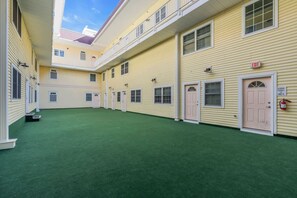 A building with multiple doors, an exit sign, and a fire extinguisher. - 4BR Rooftop Retreat Near Beach w/ Elevator & Parking (Seaside Heights)