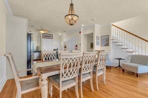 A dining area with a wooden table and chairs, a chandelier, and a staircase. - 4BR Rooftop Retreat Near Beach w/ Elevator & Parking (Seaside Heights)