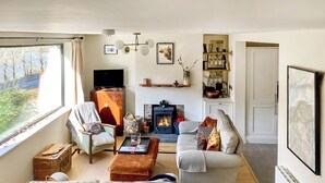Una sala de estar moderna con chimenea, televisor y un amplio ventanal con vistas a un paisaje natural.