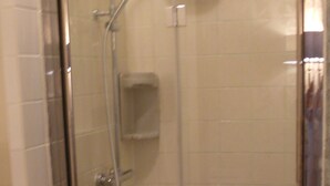Une cabine de douche fermée par des parois en verre, dotée d’un pommeau de douche à main et d’un robinet fixé au mur.