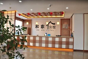 A reception desk with a sign that reads 'HE JIA HOTEL' and a modern interior design with a wooden reception desk and a plant in the foreground. - Hejia Inn Beijing Sijiqinq (Beijing)