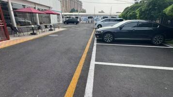 Un parking rempli de voitures, un bâtiment doté d’une terrasse, et un ciel dégagé.