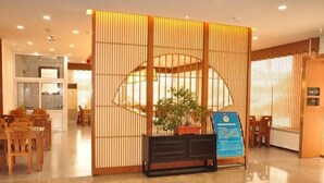 A reception area with a traditional wooden partition, a potted plant, and a blue informational sign.