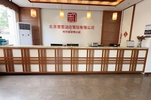 A hotel reception desk with a modern design, featuring a wooden panel and a digital screen. - Hejia Inn Beijing Sijiqinq (Beijing)