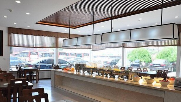 A modern restaurant with a long counter, wooden chairs, and a view of parked cars outside.