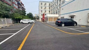 A parking lot with marked parking spaces and a building with multiple floors and balconies.