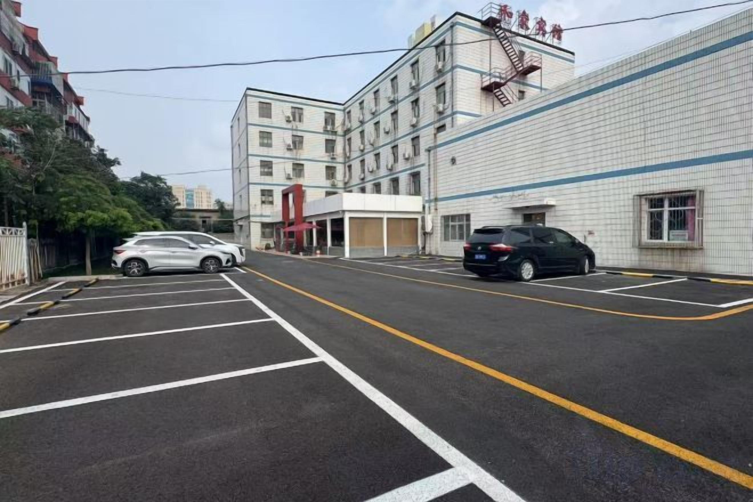 A parking lot with two cars, a building with a sign, and a clear sky.