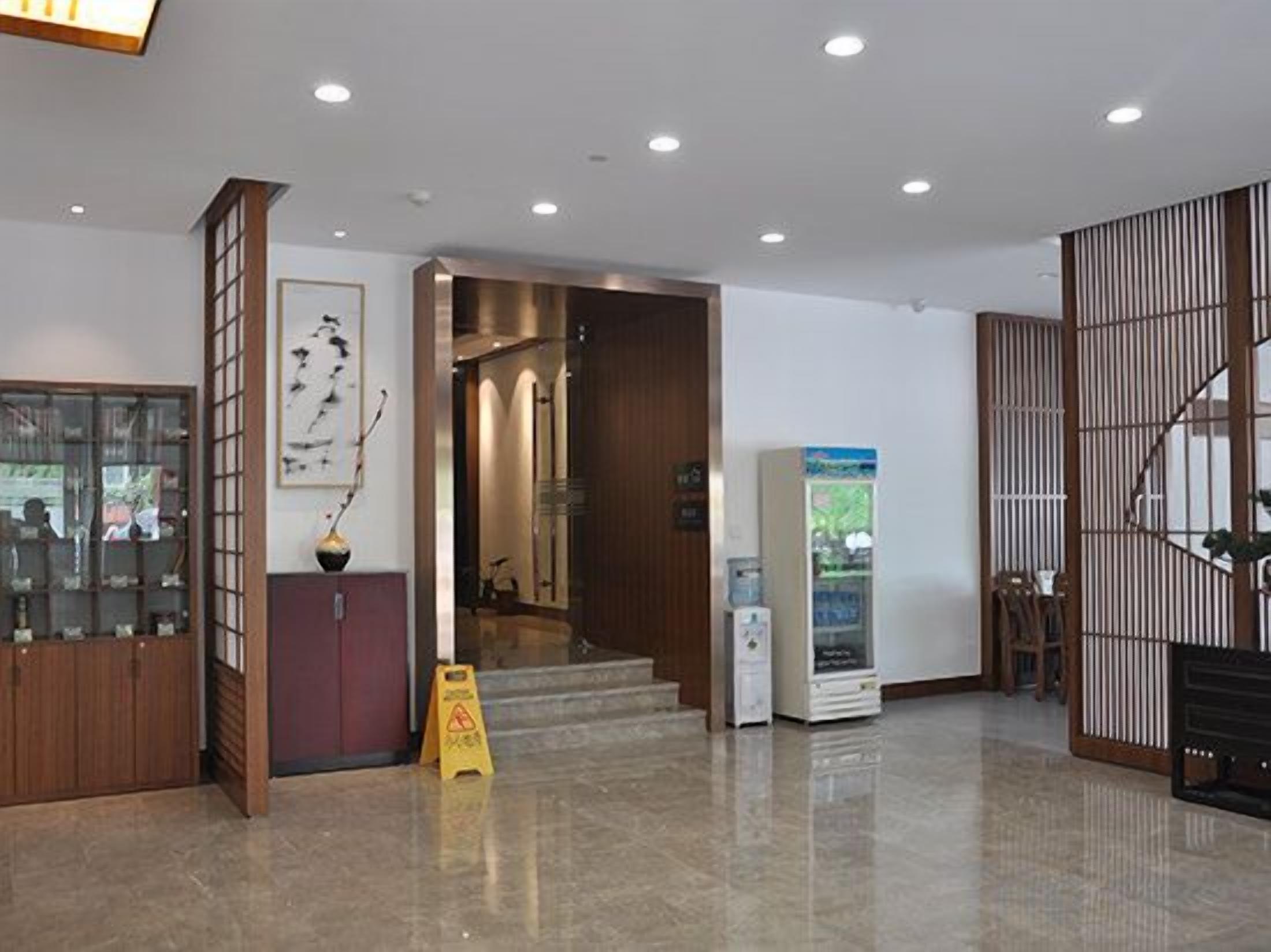 A hotel lobby with a reception desk, a vending machine, and a staircase leading to another floor.