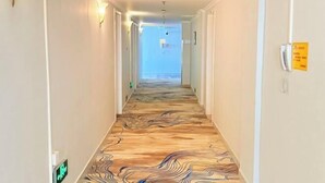 A hallway with a patterned floor, light fixtures, and a sign on the wall.
