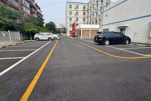 A parking lot with marked spaces and a building in the background. - Hejia Inn Beijing Sijiqinq (Beijing)