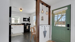 A kitchen with white cabinets, a microwave, and a wooden dining table with chairs. - Spacious & Updated 4-bedroom home w/BBQ, fire pit & AC in the Heart of Missoula! (Missoula)