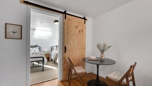 A room with a wooden sliding door, a round table with a vase, and two wooden chairs. - Spacious & Updated 4-bedroom home w/BBQ, fire pit & AC in the Heart of Missoula! (Missoula)