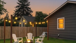 A backyard with a fire pit and three Adirondack chairs. - Spacious & Updated 4-bedroom home w/BBQ, fire pit & AC in the Heart of Missoula! (Missoula)