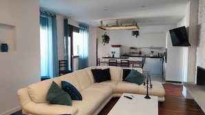 A living room with a beige sectional sofa, a white coffee table, and a TV mounted on the wall. - Elegant Apartment with Terrace – A Peaceful Oasis in Palermo (Palermo)