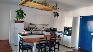 A modern kitchen with white cabinets, a wooden dining table, and four chairs. There is a built-in oven and a microwave on the countertop. - Elegant Apartment with Terrace – A Peaceful Oasis in Palermo (Palermo)
