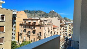 A multi-story residential building with balconies, a mountain in the background, and a clear sky.