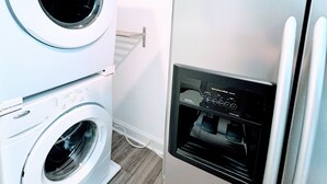 A compact laundry room with a front-loading washer and dryer, a built-in water dispenser, and a stainless steel refrigerator. - “See you by the wall” Duke region (Durham)