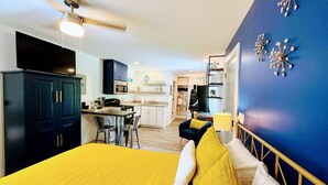 A compact hotel room with a bed, a desk, a chair, and a kitchenette. - “See you by the wall” Duke region (Durham)