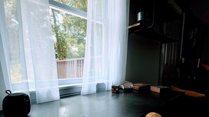 A room with a large window, a wooden bench, a small table with a Rubik's cube, and a kettle. - “See you by the wall” Duke region (Durham)