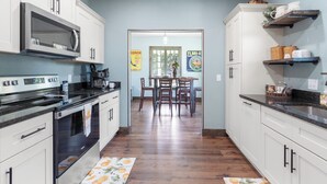 A kitchen with white cabinets, a microwave, and a stove. There is a dining area with a table and chairs.
