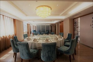 Een vergaderruimte met een ronde tafel, stoelen en een kroonluchter.