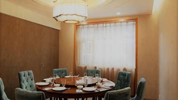 A conference room with a round table, green upholstered chairs, and a chandelier.