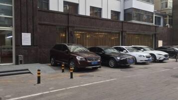 Rivissä parkkeerattuja autoja tumman julkisivun ja useiden ikkunoiden omaavan rakennuksen edessä.