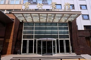 A hotel entrance with a glass facade and a revolving door.