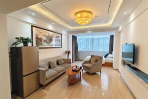 Una sala de estar moderna con sofá, sillón, mesa de centro, televisor y una obra de arte en la pared.