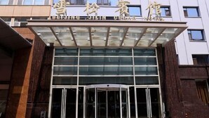 A hotel entrance with a revolving door and large glass windows. - Xuesong Hostel (Beijing)