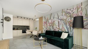 A modern living room with a green sofa, a round coffee table, and a minimalist kitchen in the background. - Comfortable Apartment, Sauna and Indoor Pool (Dziwnów)