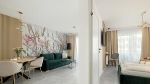 A modern hotel room with a green sofa, a dining table, and a large floral artwork on the wall. - Comfortable Apartment, Sauna and Indoor Pool (Dziwnów)