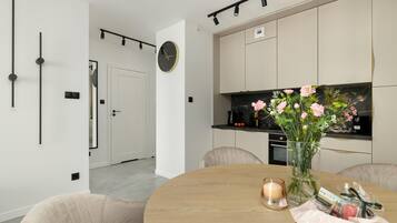Una cocina moderna con encimera de mármol, un reloj y un florero con flores sobre la mesa.